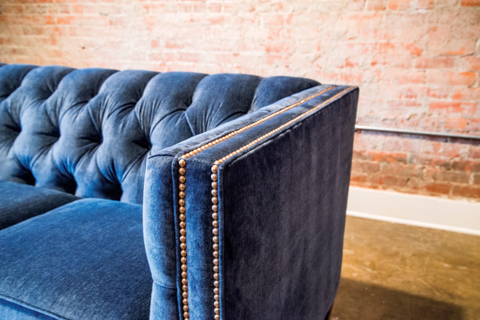 Blue velvet couch with gold detailing sold at Millers Furniture